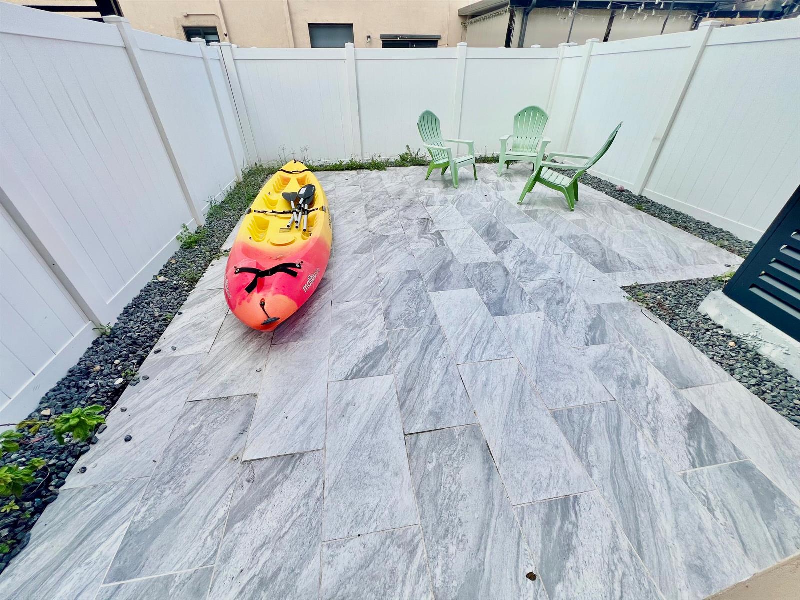 A patio with gray stone tiles, a yellow and orange kayak, and three green chairs — 10490 W 33rd Way, Hialeah FL 33018, HIALEAH, FL