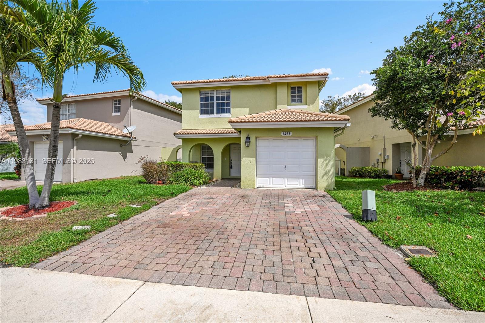 A two-story house with a light green exterior, a tiled roof, and a brick driveway — 6767 Duval Ave, West Palm Beach FL 33411, WEST PALM BEACH, FL