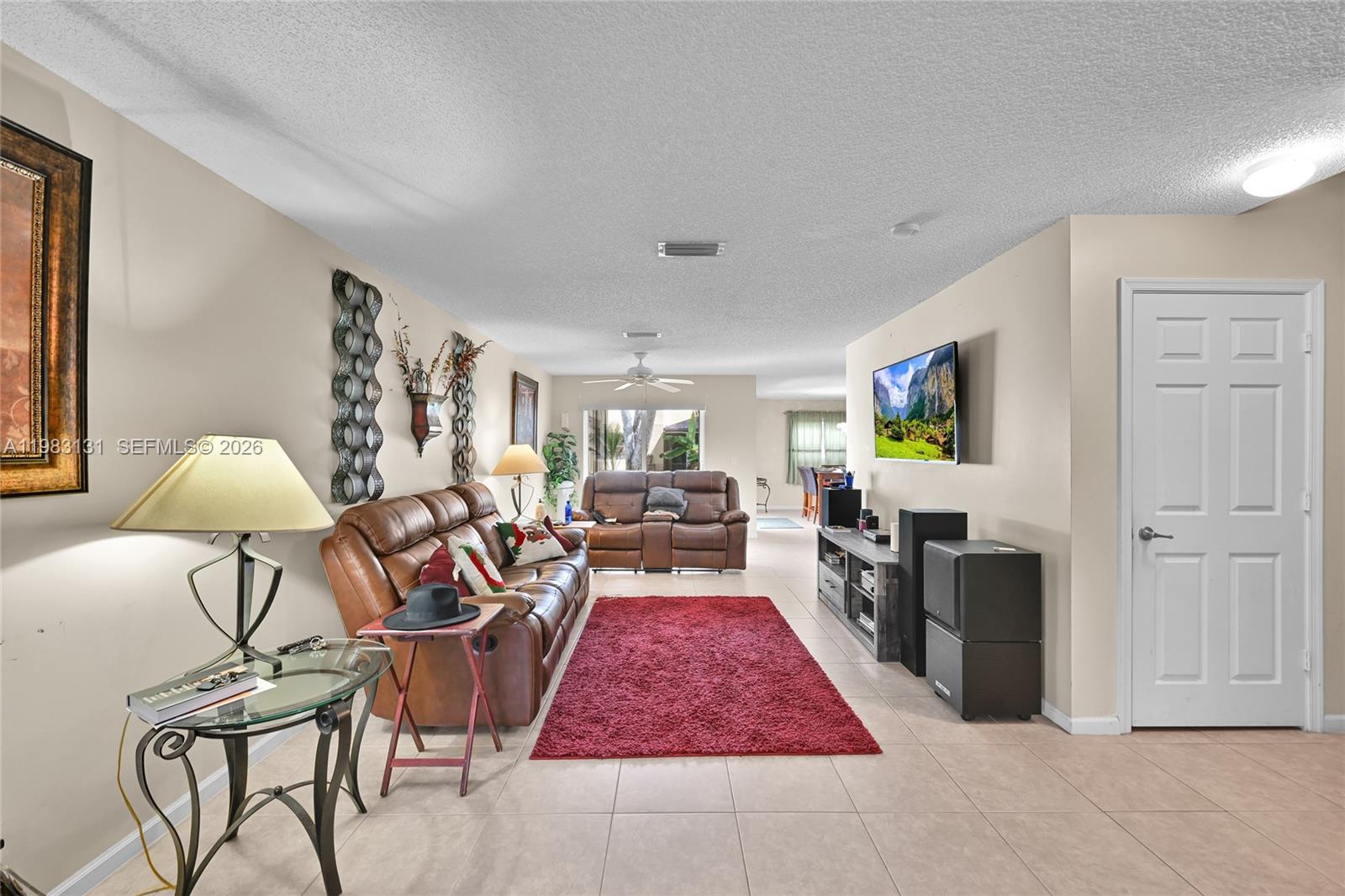 A living room features a brown leather sofa, a red rug, and a wall-mounted television — 6767 Duval Ave, West Palm Beach FL 33411, WEST PALM BEACH, FL