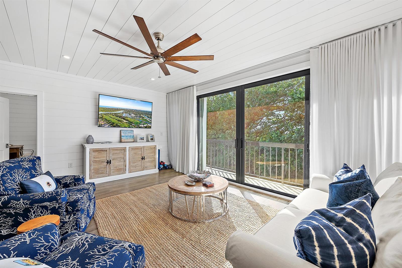 A living room features white shiplap walls, a ceiling fan, and sliding glass doors — 70 Celestial Way # 208, Juno Beach FL 33408, JUNO BEACH, FL