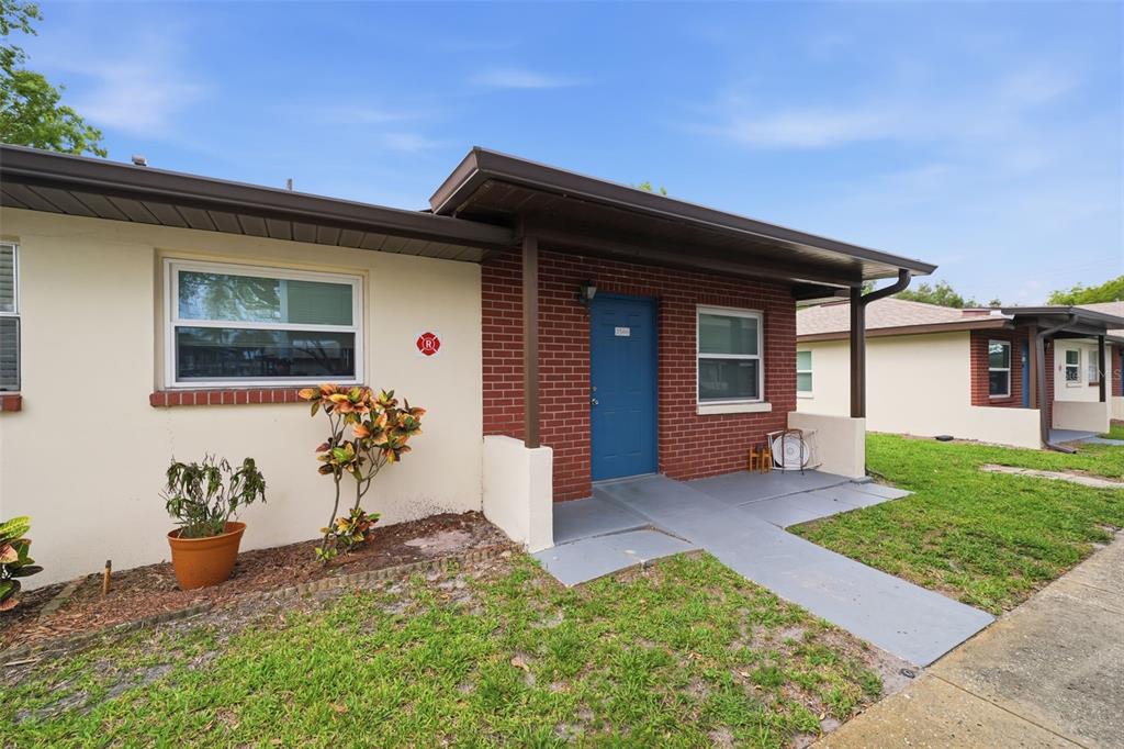 A single-story brick and stucco house with a blue front door and a concrete walkway — 24862 US HIGHWAY 19 N UNIT 3506, CLEARWATER, FL