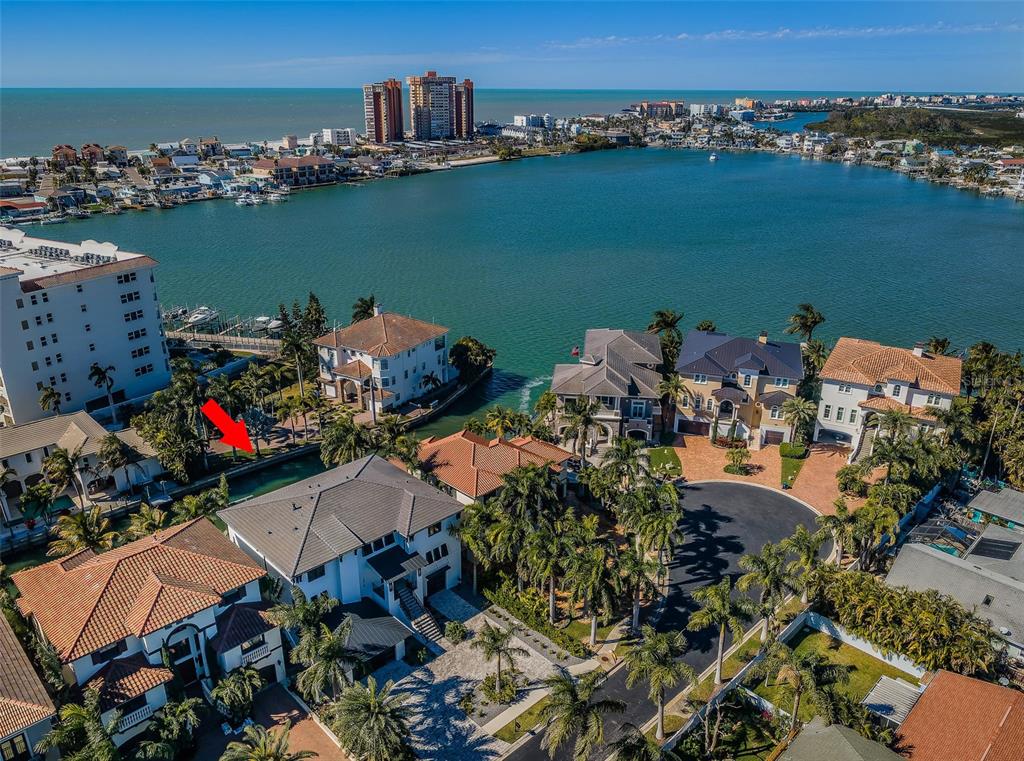 An aerial view shows luxury waterfront homes along a canal with a red arrow pointing down — 218 SYDNEY LANE, REDINGTON SHORES, FL