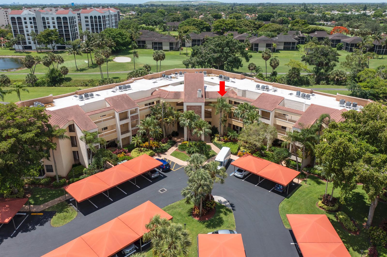 An aerial view of a multi-story apartment complex with covered parking and surrounding landscaping — 7520 La Paz Boulevard # 104, Boca Raton FL 33433, BOCA RATON, FL