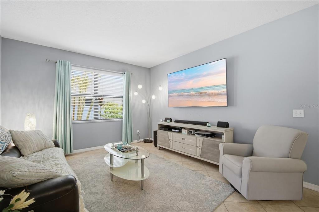 A living room features a wall-mounted television, a media console, a sofa, and an armchair — 11604 SUNBURST MARBLE ROAD, RIVERVIEW, FL