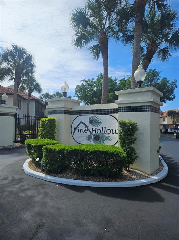 A beige stucco entrance sign for Pine Hollow stands in front of palm trees — 307 PINE HOLLOW CIRCLE UNIT 307, ENGLEWOOD, FL