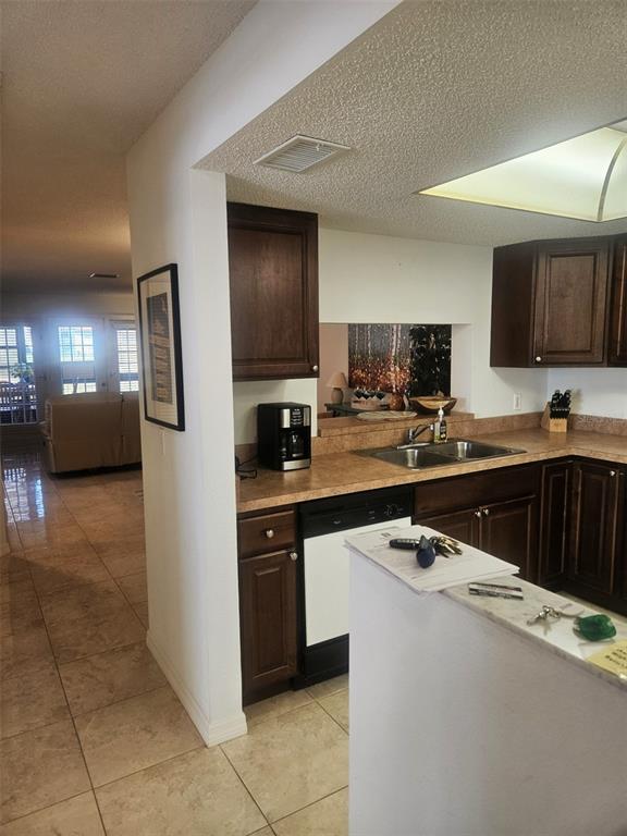 A kitchen with dark wood cabinets, laminate countertops, and a pass-through window to the living area — 307 PINE HOLLOW CIRCLE UNIT 307, ENGLEWOOD, FL