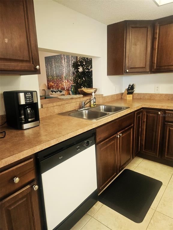 A kitchen features dark wood cabinets, laminate countertops, a double sink, and a black dishwasher — 307 PINE HOLLOW CIRCLE UNIT 307, ENGLEWOOD, FL