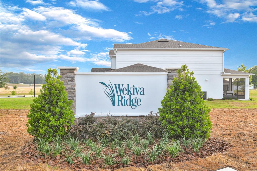 A white neighborhood entrance sign for Wekiva Ridge stands in front of a house — 1010 CLOUD RIDGE COURT, MOUNT DORA, FL