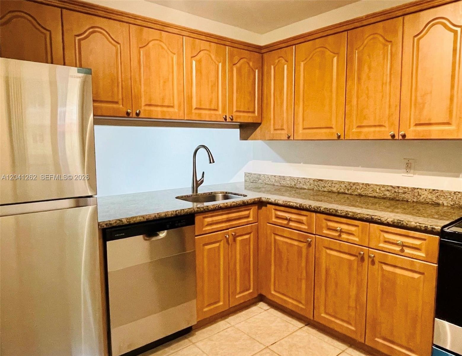 A kitchen features light wood cabinets, granite countertops, and stainless steel appliances — 7730 Camino Real # F113, Miami FL 33143, MIAMI, FL