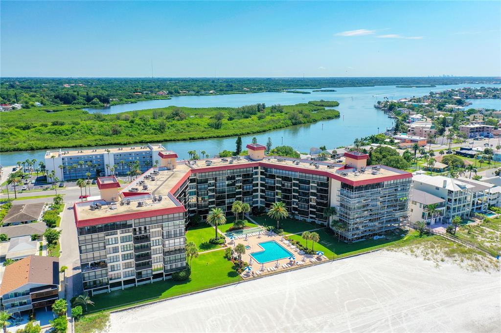 An aerial view of a multi-story beachfront condominium complex with a swimming pool and lawn — 18304 GULF BOULEVARD UNIT 516, REDINGTON SHORES, FL