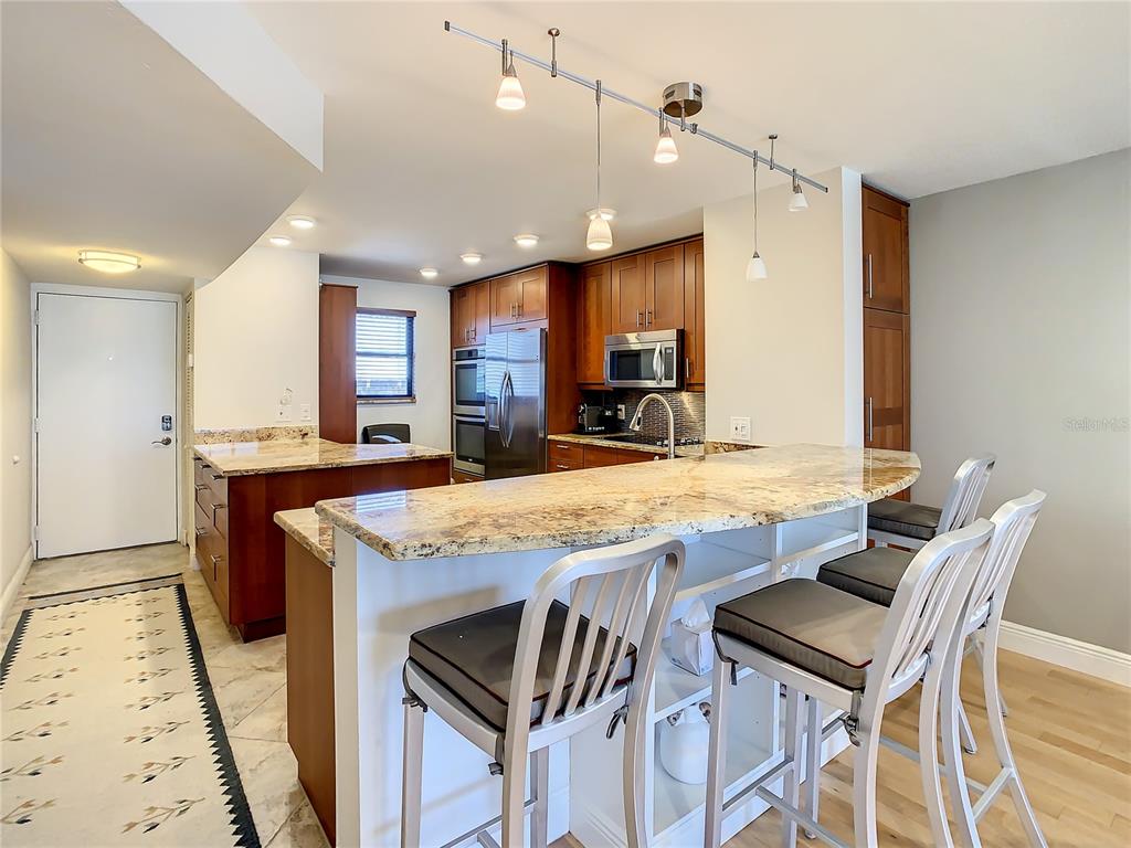 A kitchen features granite countertops, wood cabinetry, stainless steel appliances, and a breakfast bar — 18304 GULF BOULEVARD UNIT 516, REDINGTON SHORES, FL