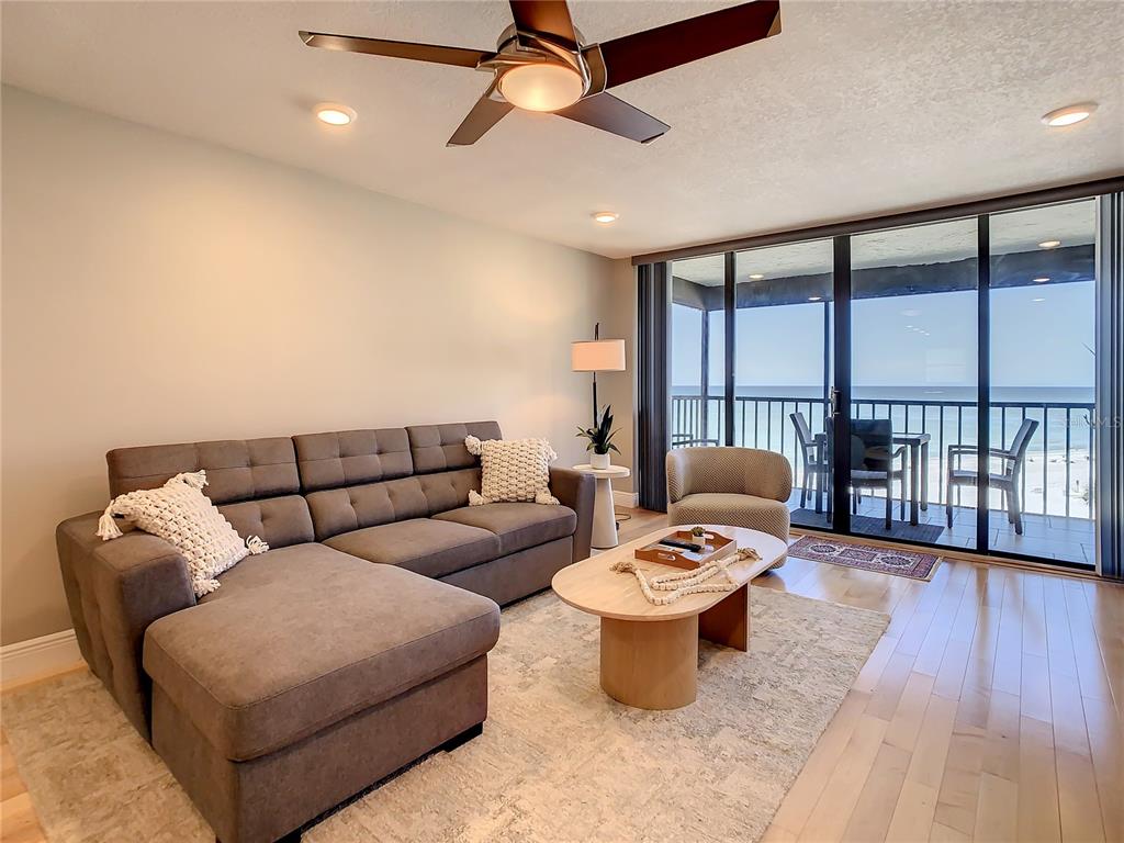A living room with a gray sectional sofa, coffee table, and sliding doors to a balcony — 18304 GULF BOULEVARD UNIT 516, REDINGTON SHORES, FL
