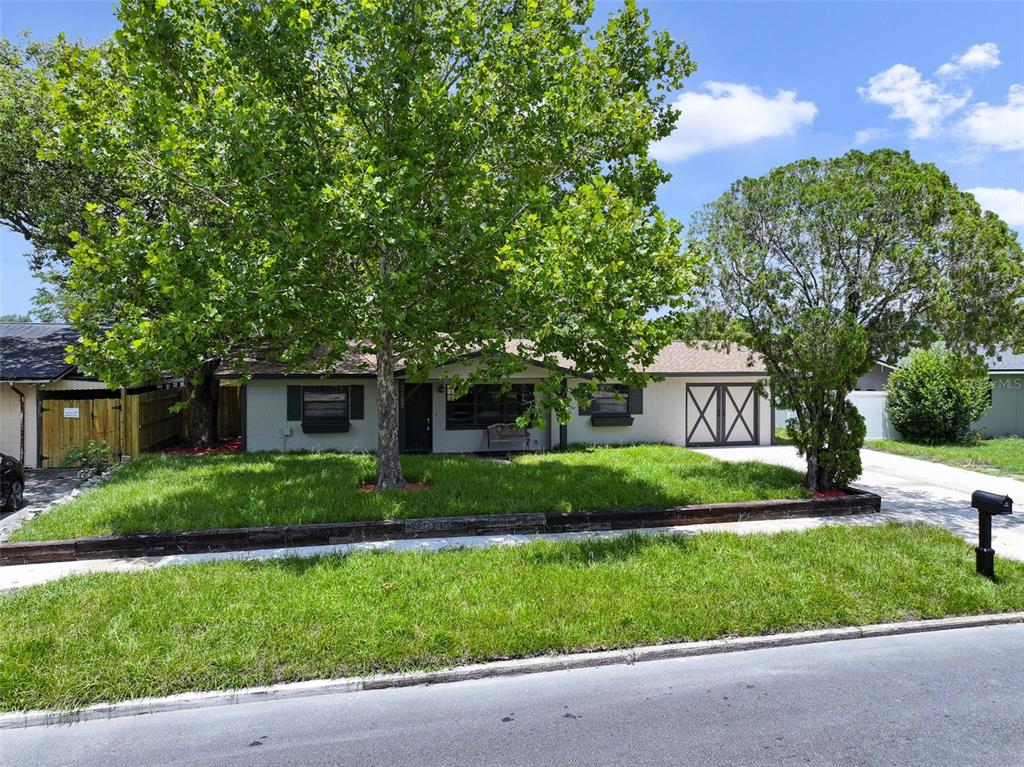 A single-story house with a lawn, large trees, and a garage with double doors — 7107 LEIGHTON WAY, ORLANDO, FL