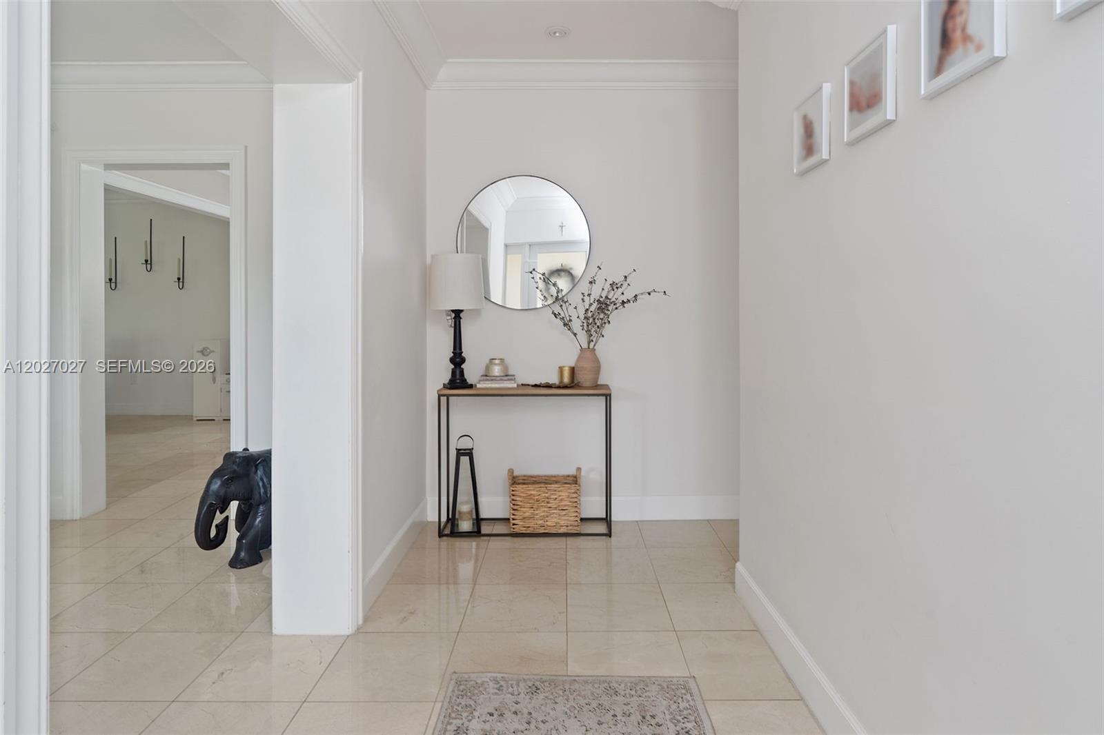 A bright hallway features light tile flooring, a console table with decor, and wall art — 4750 Alhambra Cir, Coral Gables FL 33146, CORAL GABLES, FL