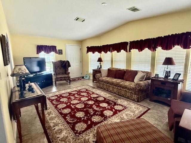 A living room features a patterned sofa, a red area rug, and a television console — 197 PHILADELPHIA BOULEVARD UNIT 26, PALM HARBOR, FL