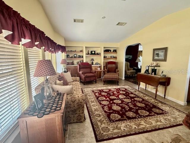A living room features a patterned area rug, a sofa, armchairs, and built-in shelving — 197 PHILADELPHIA BOULEVARD UNIT 26, PALM HARBOR, FL