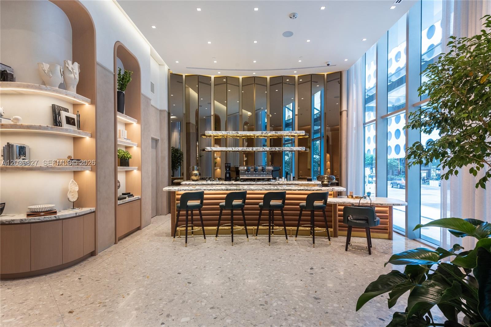 A modern coffee bar features marble counters, gold-toned mirrored walls, and stools on terrazzo flooring — 77 SE 5th St # 3206, Miami FL 33131, MIAMI, FL