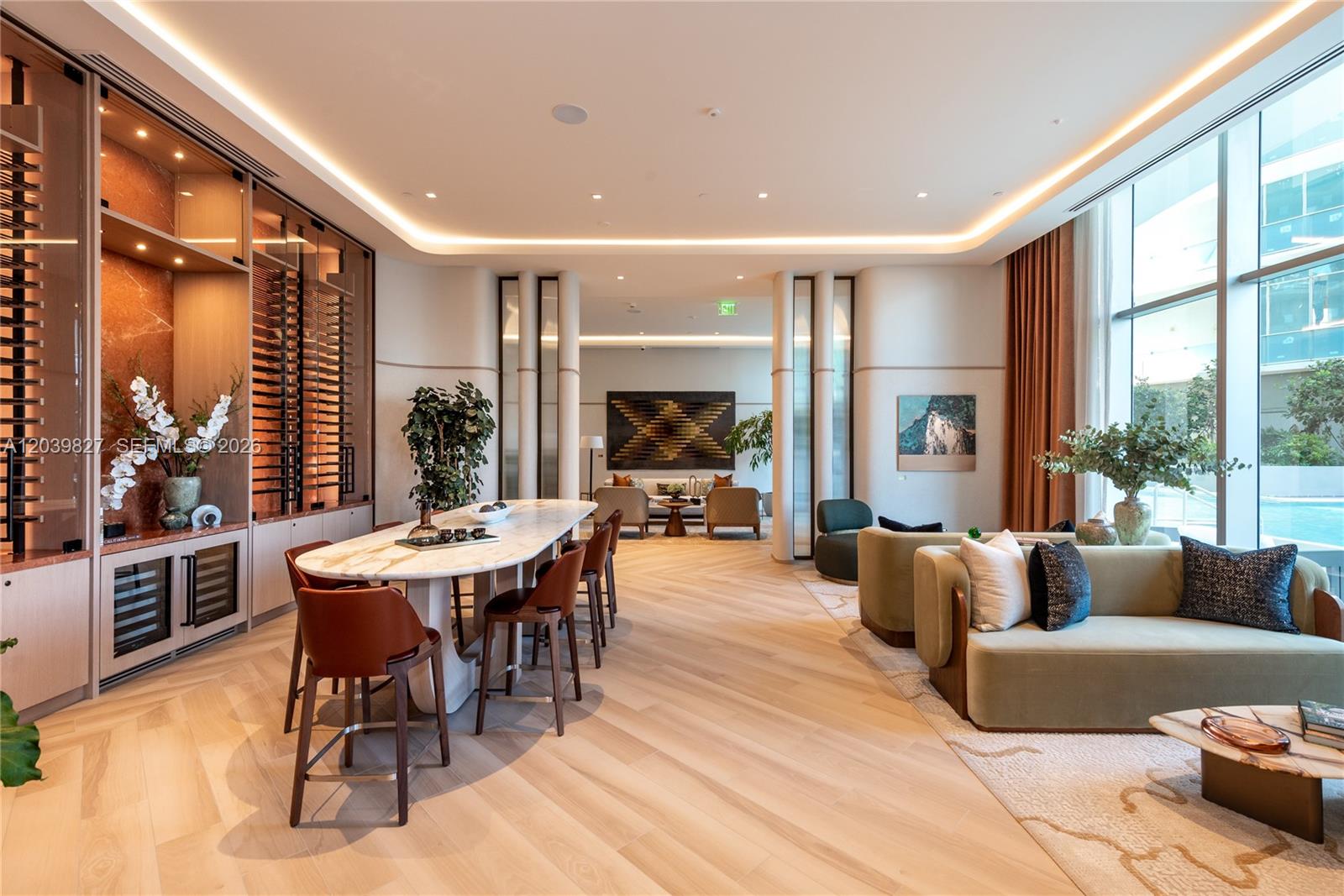 A modern lounge features a marble-topped bar, wine storage, and a seating area with sofas — 77 SE 5th St # 3206, Miami FL 33131, MIAMI, FL