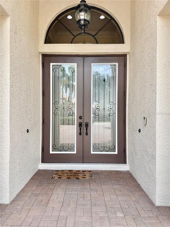 A brown double front door with glass inserts sits beneath an arched transom window — 6919 DOMINION LANE, LAKEWOOD RANCH, FL