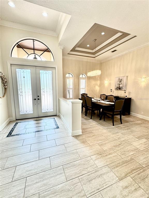 A dining room with a tray ceiling and tile floors sits adjacent to a front entryway — 6919 DOMINION LANE, LAKEWOOD RANCH, FL