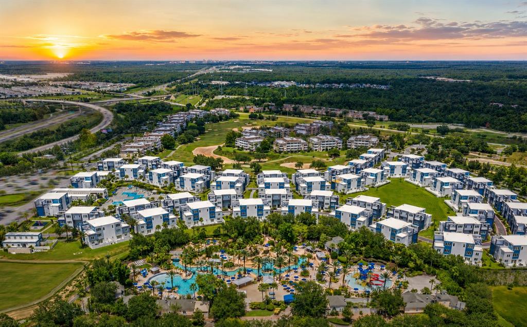 An aerial view shows a resort complex with multiple apartment buildings and a large pool — 7740 SANDY RIDGE DRIVE UNIT 135, REUNION, FL