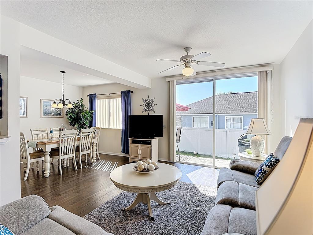 A living room with wood flooring, a gray rug, and a dining area visible — 565 ORCHID DRIVE, DAVENPORT, FL