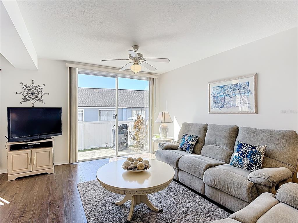 A living room features a grey sofa, circular coffee table, television, and sliding glass doors — 565 ORCHID DRIVE, DAVENPORT, FL
