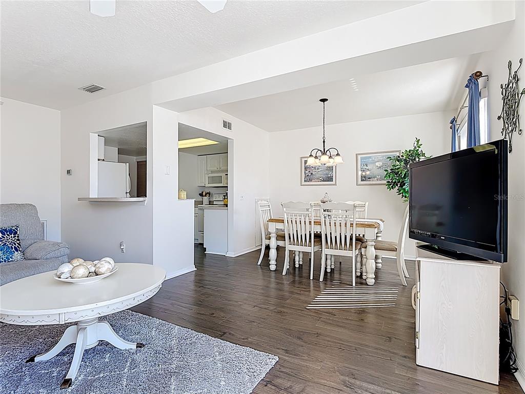 A living and dining area features dark wood floors, white walls, and a pass-through kitchen — 565 ORCHID DRIVE, DAVENPORT, FL