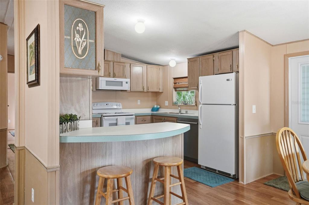 A kitchen with light wood cabinets, a white refrigerator, and a breakfast bar with stools — 5161 FOREST GLENN DRIVE, SPRING HILL, FL