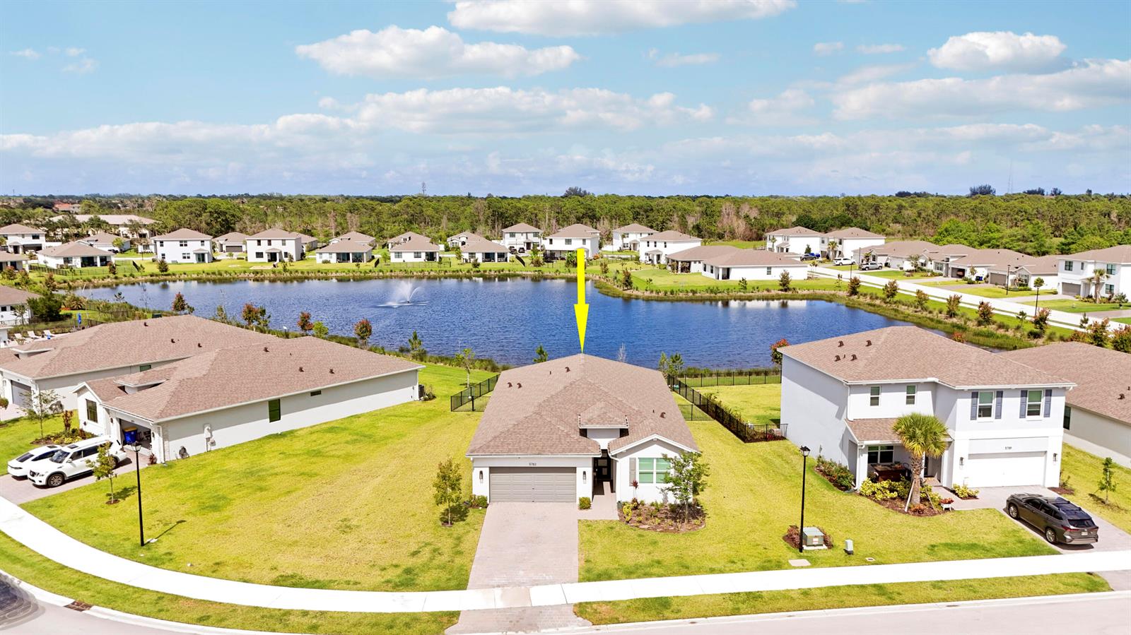 An aerial view shows a single-story suburban house with a garage facing a lake — 5783 SE Skyblue Circle, Stuart FL 34997, STUART, FL