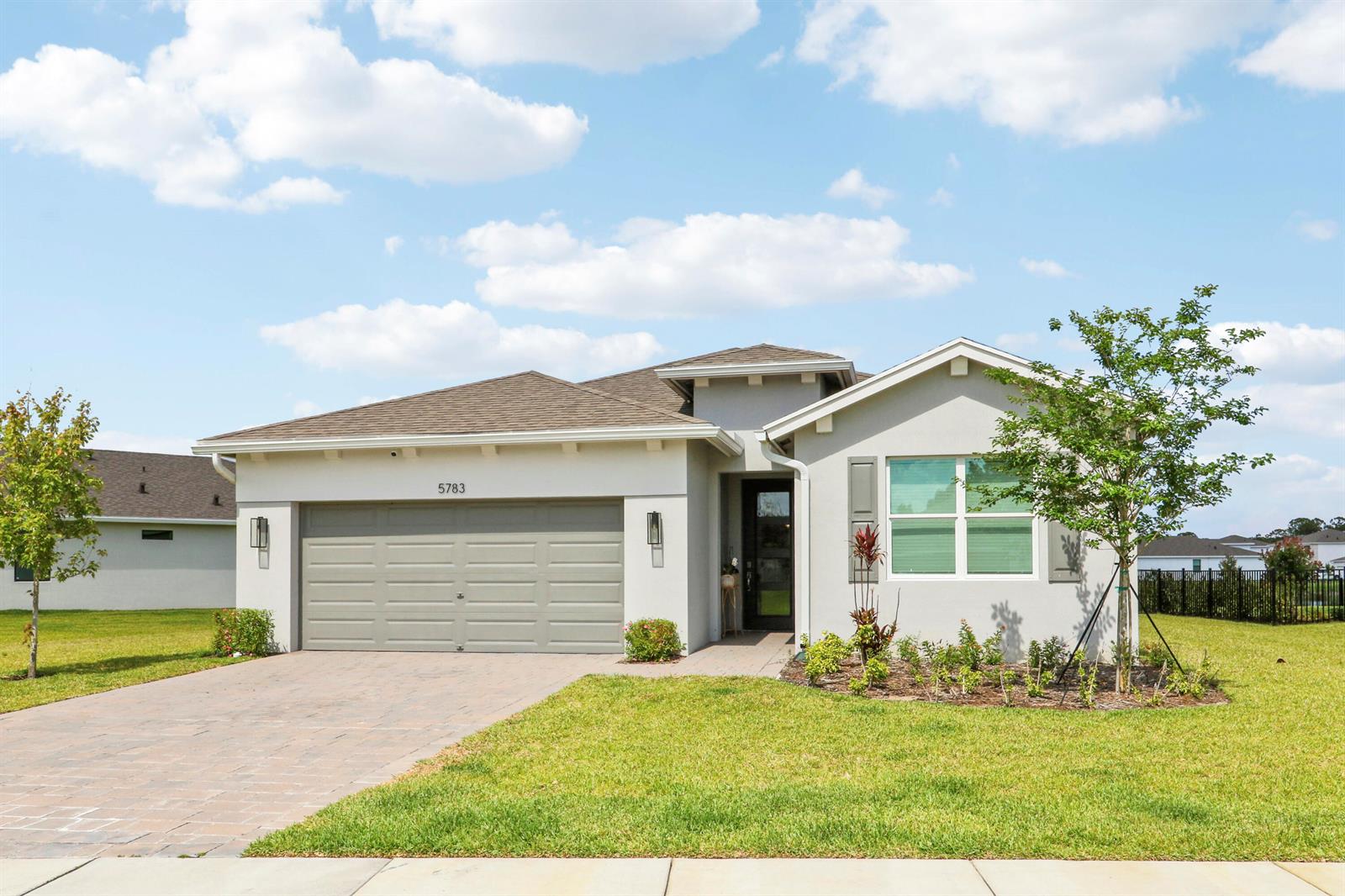 A single-story house with a two-car garage, light stucco exterior, and a paved driveway — 5783 SE Skyblue Circle, Stuart FL 34997, STUART, FL