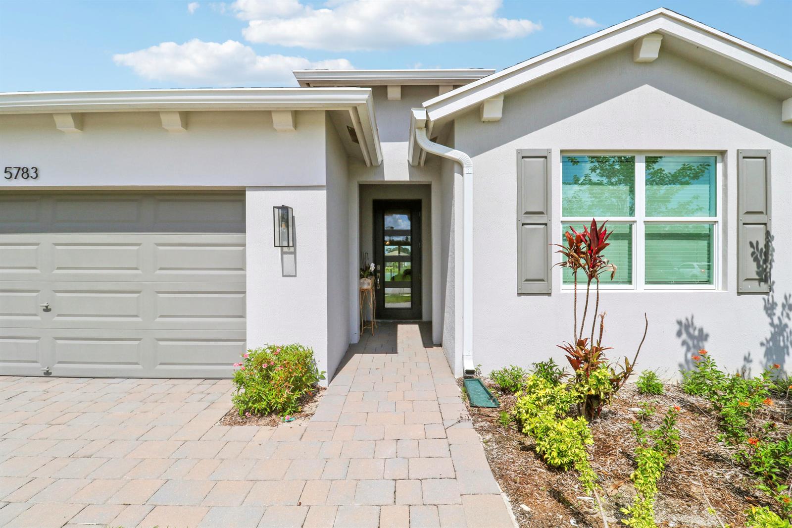 The exterior of a house features a paved walkway, a garage, and a front entrance — 5783 SE Skyblue Circle, Stuart FL 34997, STUART, FL