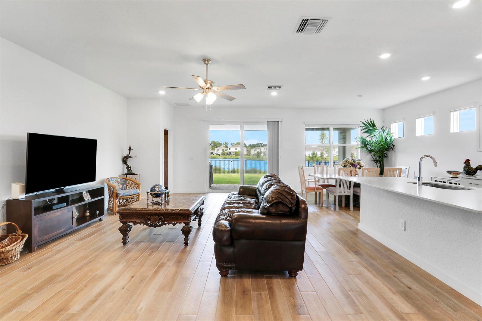 An open-concept living and dining area features wood-look tile floors and a view of water — 5783 SE Skyblue Circle, Stuart FL 34997, STUART, FL