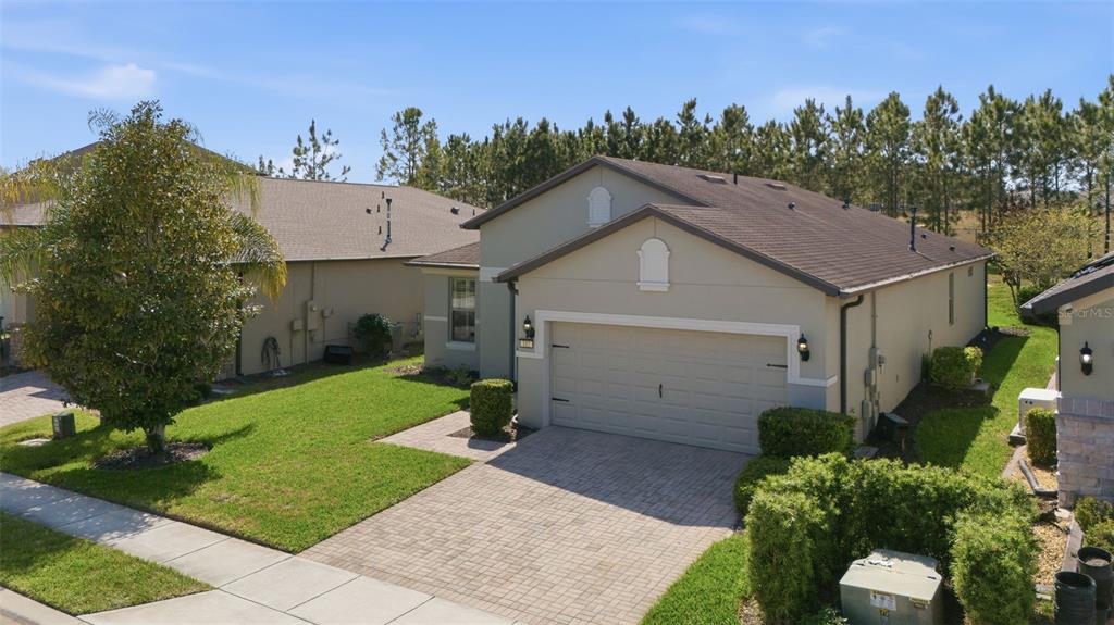 An aerial view shows a single-story house with a paved driveway and a green lawn — 112 CASTELLON COURT, DAVENPORT, FL