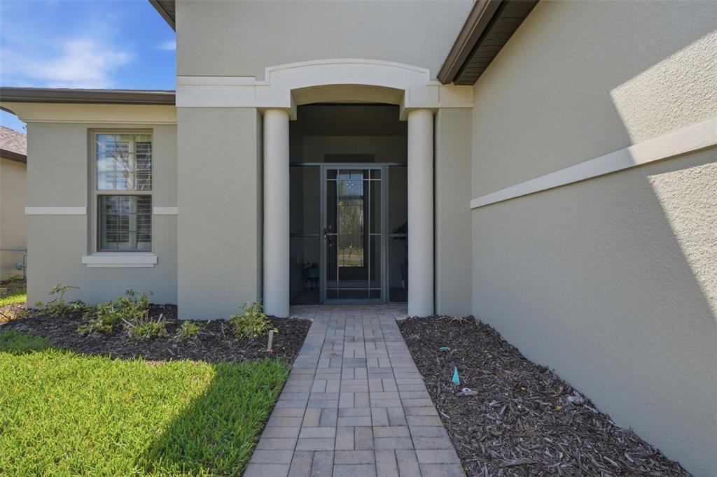 A paved walkway leads to a covered front entrance with two white columns — 112 CASTELLON COURT, DAVENPORT, FL