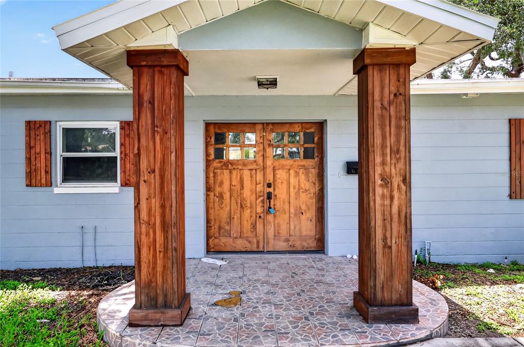A light blue house exterior features a covered porch with two large wooden support columns — 120 81ST AVENUE NE, ST PETERSBURG, FL