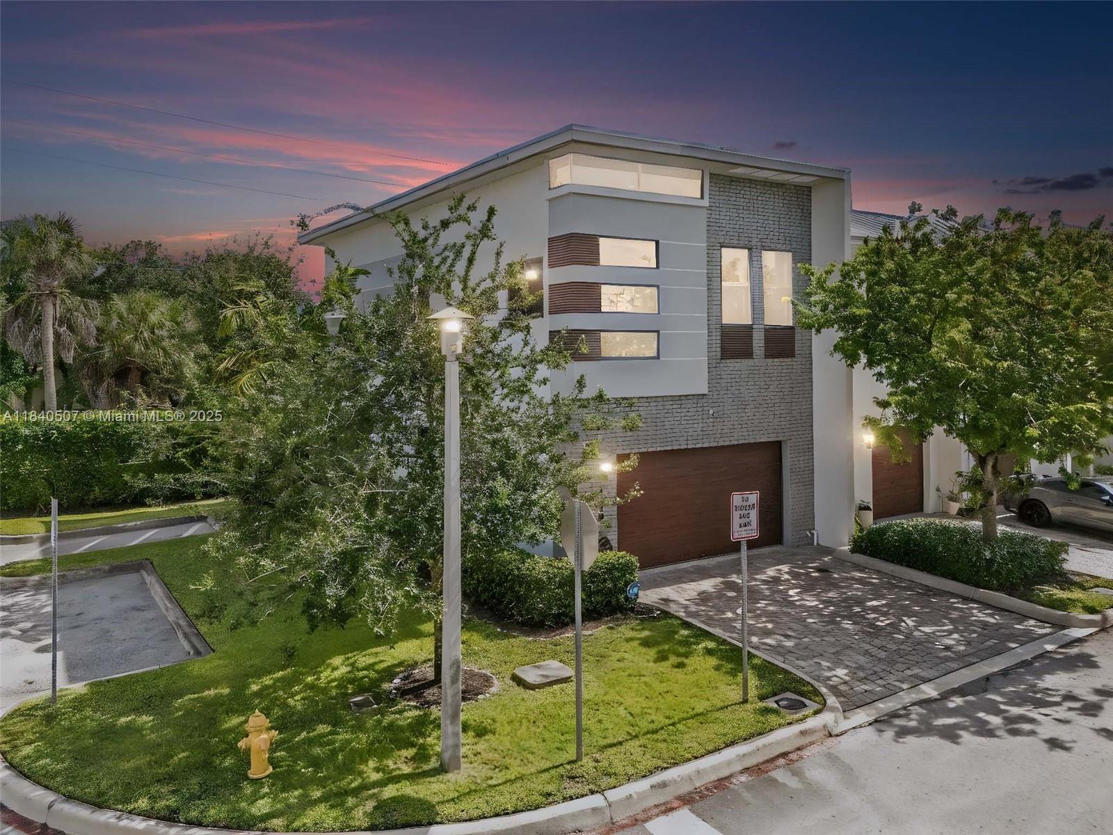 A modern two-story townhouse features a brick facade, a wooden garage door, and landscaping — 4460 NW 8th Pl, Plantation FL 33317, PLANTATION, FL