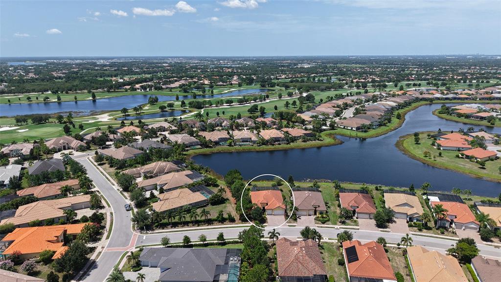 An aerial view shows a residential neighborhood with a circled house near a lake — 7005 WHITTLEBURY TRAIL, LAKEWOOD RANCH, FL