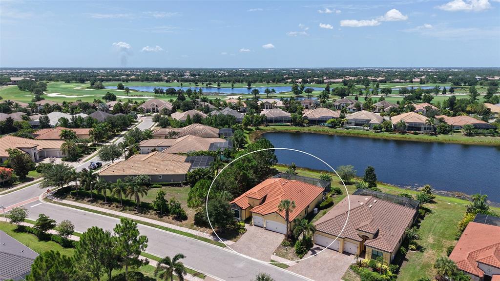 An aerial view shows a residential house with a tiled roof near a lake — 7005 WHITTLEBURY TRAIL, LAKEWOOD RANCH, FL