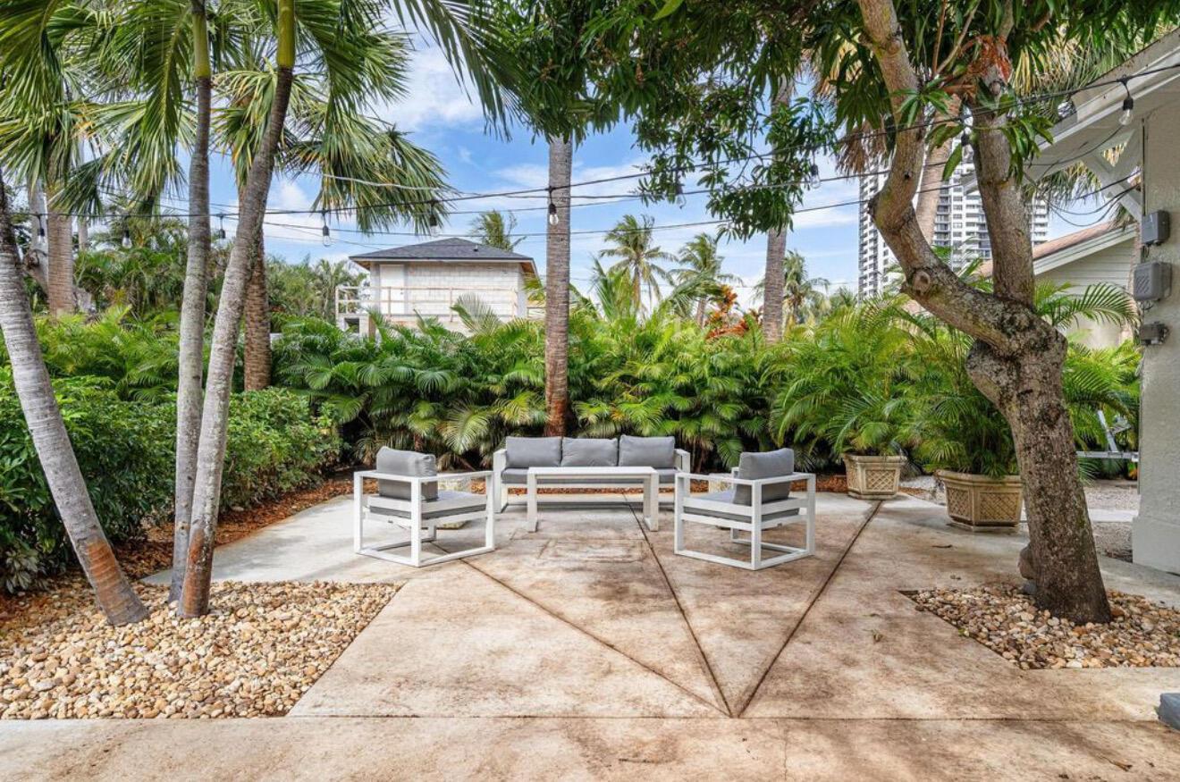 A patio features white outdoor furniture set on a concrete slab surrounded by tropical landscaping — 5301 N Flagler Drive, West Palm Beach FL 33407, WEST PALM BEACH, FL