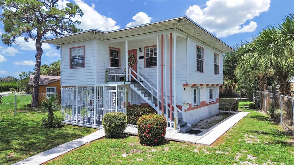 A two-story house with white siding, a raised front porch, and a fenced ground-level area — 2371 7TH STREET S, ST PETERSBURG, FL
