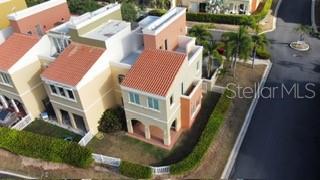 An aerial view shows a multi-story townhouse with a red tile roof and arched entryway — VIA CAPRI # 8 AQUABELLA UNIT 117, HUMACAO, PR