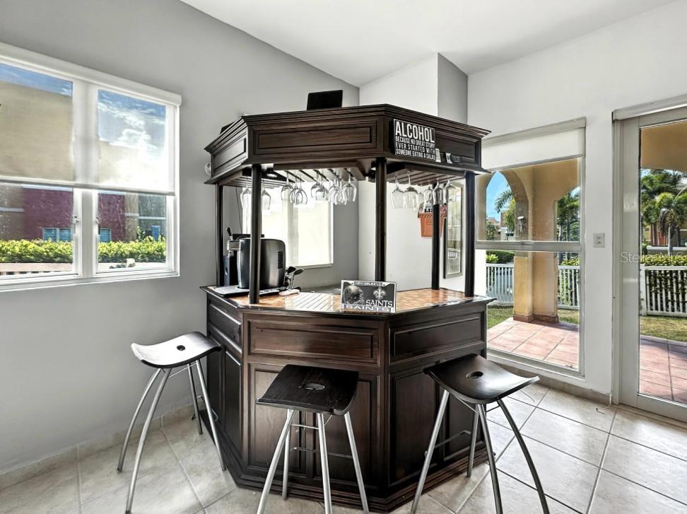 A dark wood home bar with three stools sits in a room with tile floors — VIA CAPRI # 8 AQUABELLA UNIT 117, HUMACAO, PR
