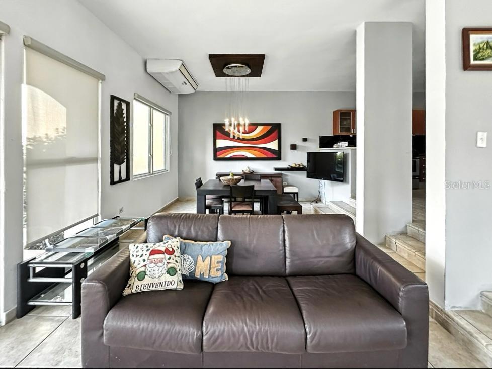 A living room with a brown leather sofa faces a dining area with modern decor — VIA CAPRI # 8 AQUABELLA UNIT 117, HUMACAO, PR