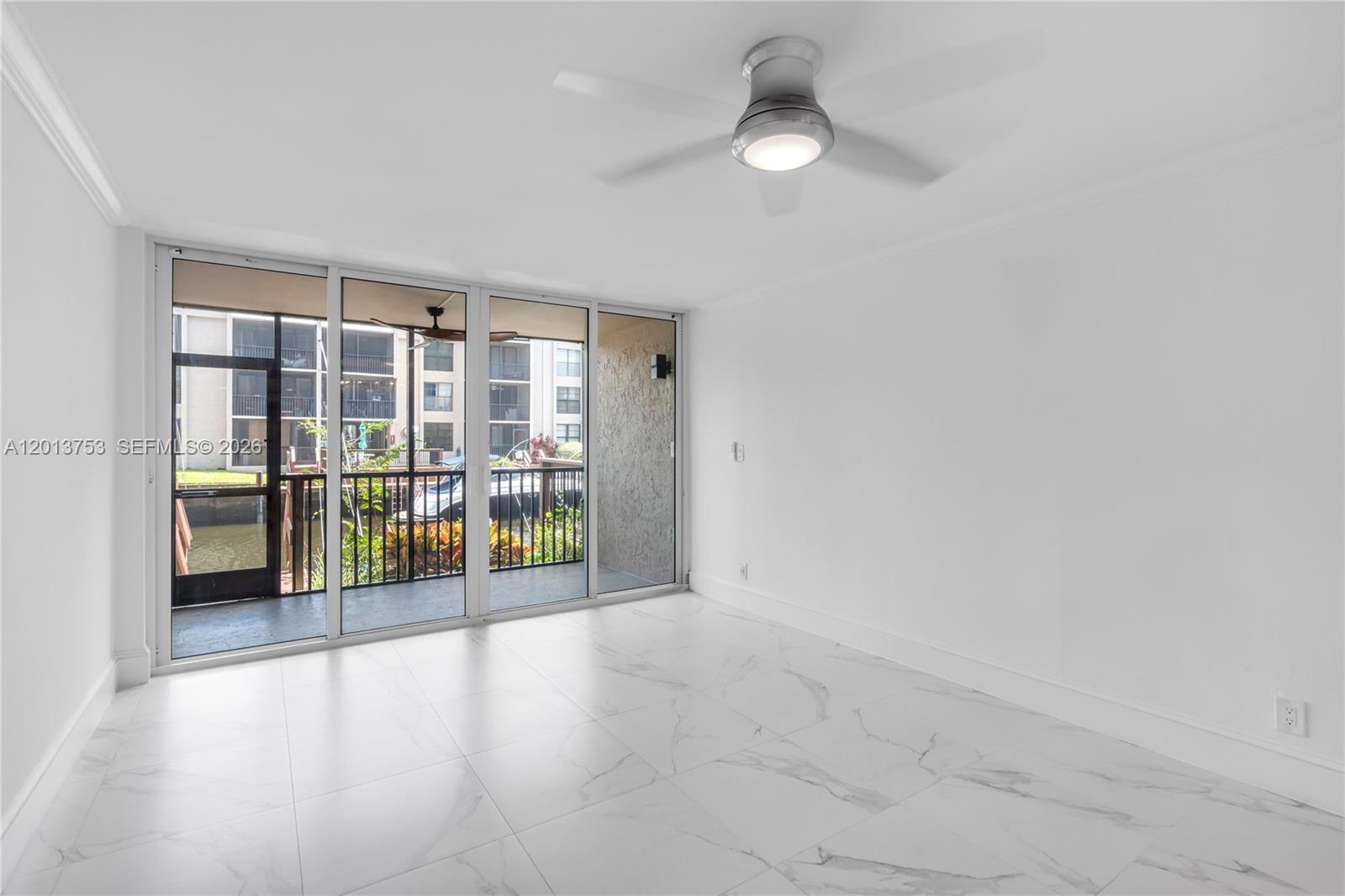 A bright room features white marble-look tile flooring, a ceiling fan, and sliding glass balcony doors — 12 Royal Palm Way # 103, Boca Raton FL 33432, BOCA RATON, FL