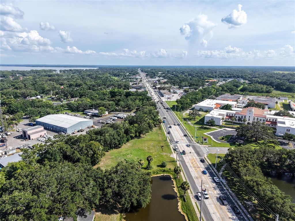 Aerial view of a multi-lane road passing through a wooded area with commercial buildings — S 14TH STREET, LEESBURG, FL