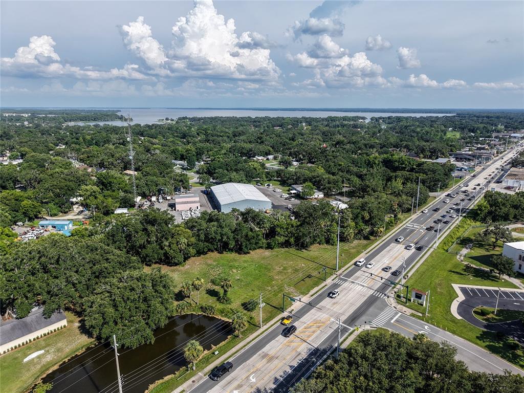 An aerial view shows a multi-lane road, a large warehouse building, and a small pond — S 14TH STREET, LEESBURG, FL