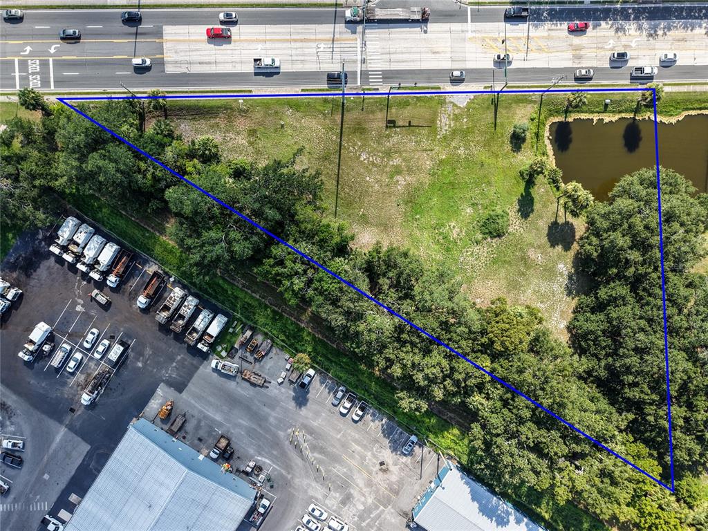 An aerial view shows a triangular vacant lot bordered by a road, trees, and water — S 14TH STREET, LEESBURG, FL