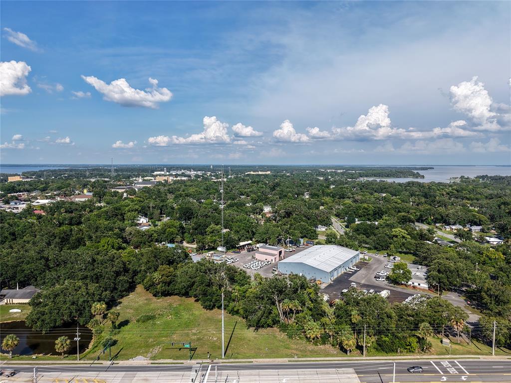 An aerial view shows a commercial building with a parking lot surrounded by dense trees — S 14TH STREET, LEESBURG, FL