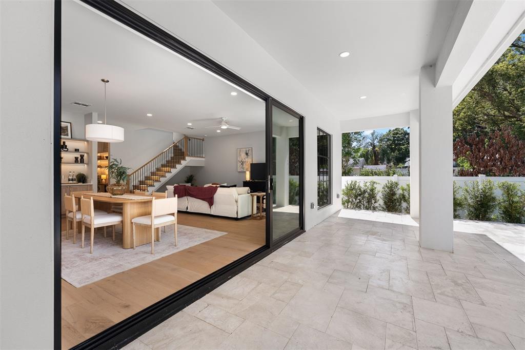 A covered patio with stone flooring overlooks an open-concept living area with a dining table — 113 W EVANS STREET, ORLANDO, FL